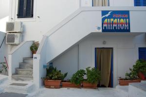 a white building with potted plants in front of a door at Aegeon Pension in Aegiali