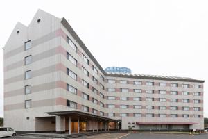 a large building with a car parked in front of it at Tabist Yabuki Station Hotel in Yabuki