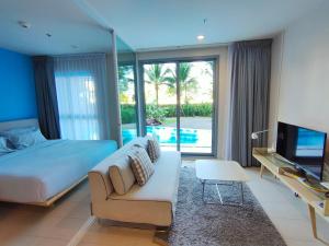 a bedroom with a bed and a couch and a tv at BLU-Pool Access in Cha Am