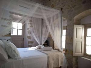 a bedroom with a white bed with a canopy at En Patmo Holiday Home in Patmos