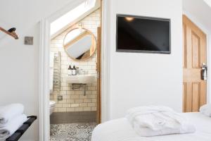 a bathroom with a bed and a television on the wall at Cliftonville Townhouse in Margate