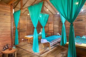 Habitación con 2 camas y cortinas azules. en Onong Resort en Bunaken