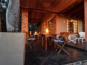 a patio with chairs and a table and a tree at Injabulo in Marloth Park