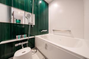 札幌市にある京王プレリアホテル札幌の緑の壁のバスルーム(白いトイレ付)