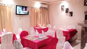 Cette chambre dispose de tables rouges, de chaises blanches et d'une télévision. dans l'établissement Hotel du Golfe de Guinee, à Conakry