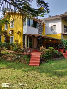a house with a yellow and white building at Leela's Cottage in Lonavala