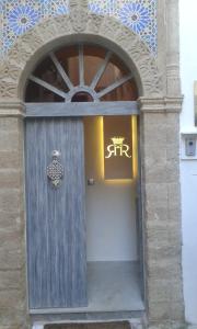 a wooden door in a building with a sign on it at Riad Raoud Rayhane in Essaouira