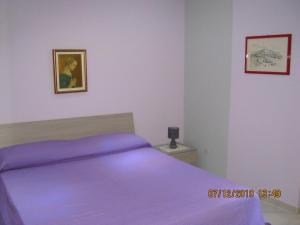 sypialnia z fioletowym łóżkiem i zdjęciem na ścianie w obiekcie Sicily Sun w mieście Lentini