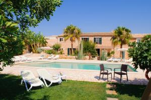 una piscina con sillas y una mesa junto a un edificio en Finca Mondrago Duri, en Portopetro