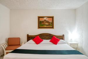 Un dormitorio con una cama con almohadas rojas y una silla en Capital O Farallon Inn, Cancún, en Cancún