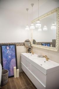 een badkamer met een witte wastafel en een spiegel bij Anita Home in Gyenesdiás