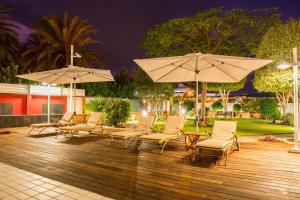 a deck with chairs and umbrellas at night at Siesta Suites in Maspalomas
