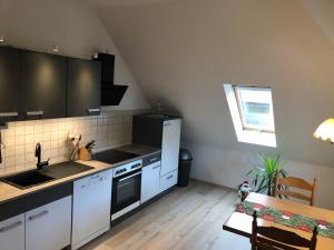 cocina con armarios blancos, fregadero y mesa en Liebetrau Apartment, en Gotha