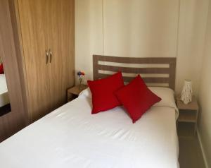 a bedroom with red pillows on a white bed at Complejo Hostelero La Fuente in Fortuna