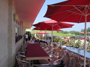 een groep tafels en stoelen met rode parasols bij Pension Arenas in Ajo