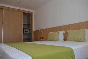 a bedroom with a large bed with a green blanket at Hotel Da Luz in Santa Maria