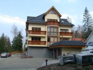 une maison avec des balcons et un homme debout devant elle dans l'établissement Apartament Super Karpacz, à Karpacz