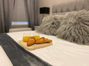 taca z rogalikami i szklanka soku pomarańczowego na łóżku w obiekcie Biskey Howe flat - FREE off-site Health Club access with Pool, Sauna, Steam Room & Gym w mieście Windermere