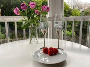 dwa kieliszki do wina i truskawki na stole z kwiatami w obiekcie Biskey Howe flat - FREE off-site Health Club access with Pool, Sauna, Steam Room & Gym w mieście Windermere