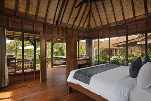 a bedroom with a bed in a room with windows at Green Space Villa in Ubud
