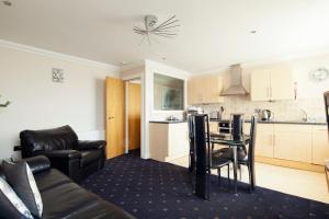 a living room with a couch and a table and a kitchen at Queens Mansions: Ocean View Apartment in Blackpool