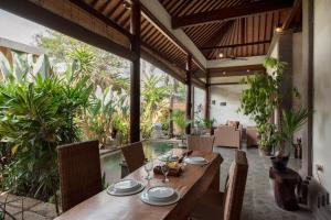 an indoor dining room with a wooden table and chairs at Bidadari Villa in Seminyak