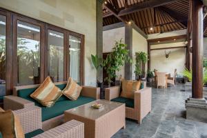 a patio with a couch and chairs and a table at Bidadari Villa in Seminyak