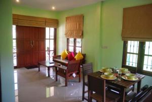 a living room with tables and chairs and windows at Anacar Bungalows in Krabi