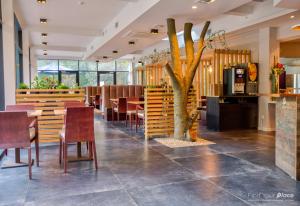 restauracja ze stołami i krzesłami oraz drzewo w środku w obiekcie Utopia Hotel - Art & Nature Hotel w mieście Mons