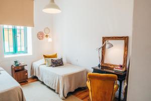 ミランデラにあるDona Fina Guest Houseのベッドルーム1室(ベッド1台、鏡、椅子付)