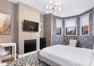 a bedroom with a bed and a flat screen tv at Suites At 143 Arlington Street in Boston