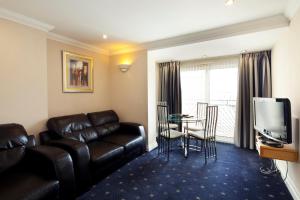 a living room with a leather couch and a television at Queens Mansions: Hesketh Apartment in Blackpool