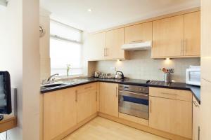 a kitchen with wooden cabinets and a sink and a stove at Queens Mansions: Hesketh Apartment in Blackpool
