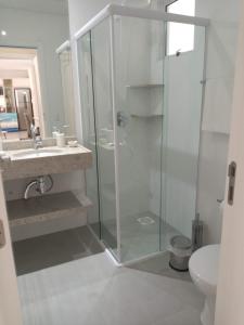 ボンビーニャスにあるMariscal 02 dormitórios, 80m do mar, com piscinaのガラスのシャワーと洗面台を備えたバスルーム