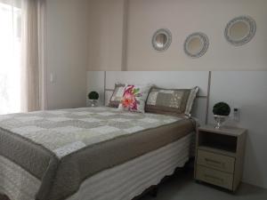 ボンビーニャスにあるMariscal 02 dormitórios, 80m do mar, com piscinaのベッドルーム1室(ベッド1台、壁に2皿)