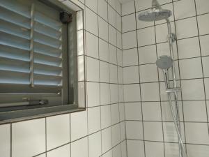 a shower in a white tiled bathroom with a window at Red Palm Village in Kralendijk