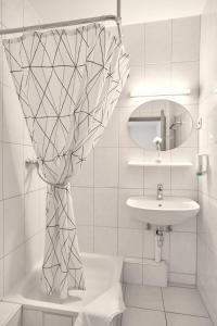 a white bathroom with a sink and a mirror at Hotel Moguntia in Mainz