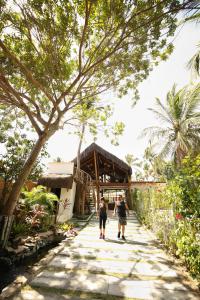 two people walking down a walkway in front of a building at Pousada Enseada Dos Golfinhos in Pipa