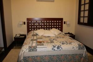 een slaapkamer met een groot bed met een houten hoofdeinde bij Auberge Suisse Pousada in Nova Friburgo