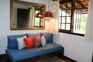 eine blaue Couch mit Kissen unter einem Spiegel in der Unterkunft Auberge Suisse Pousada in Nova Friburgo