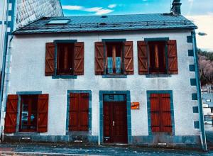 a white building with red doors and windows at Résidence Les Pâquerettes N3 in Le Mont-Dore