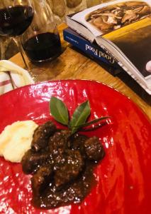 une assiette rouge de nourriture sur une table avec un livre dans l'établissement La Trigola, à Santo Stefano di Magra