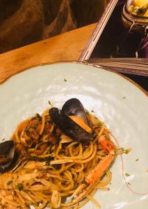 un plato de pasta con mejillones y verduras en una mesa en La Trigola, en Santo Stefano di Magra