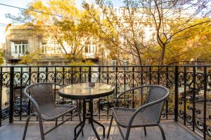 a table and chairs on a balcony with a fence at Hotello in Tbilisi City