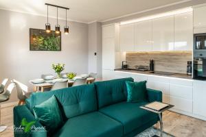 ein Wohnzimmer mit einem grünen Sofa und einer Küche in der Unterkunft Apartament Dzika Paproć in Szczawnica
