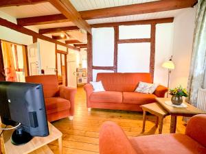 a living room with orange furniture and a tv at Reetdachkate in Neukirchen