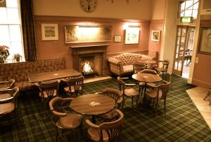 a restaurant with tables and chairs and a fireplace at Selkirk Arms Hotel in Kirkcudbright