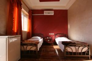 a room with two beds and a red wall at Erasmus Student House By Sunrise Hostel in Amman