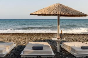 two beds and an umbrella on the beach at Alesahne Beach Hotel in Kamari