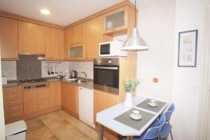 una cocina con armarios de madera y una mesa con sillas azules en Lovely Apartment at Park Güell, en Barcelona